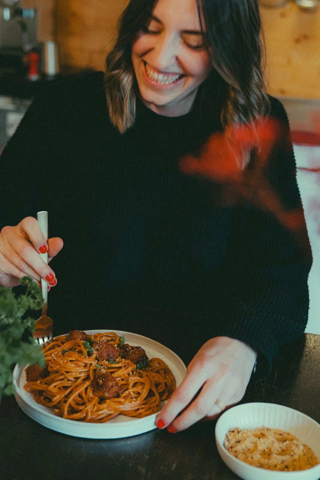Sarah Pechinger lacht beim Anrichten von Spaghetti im Home Studio