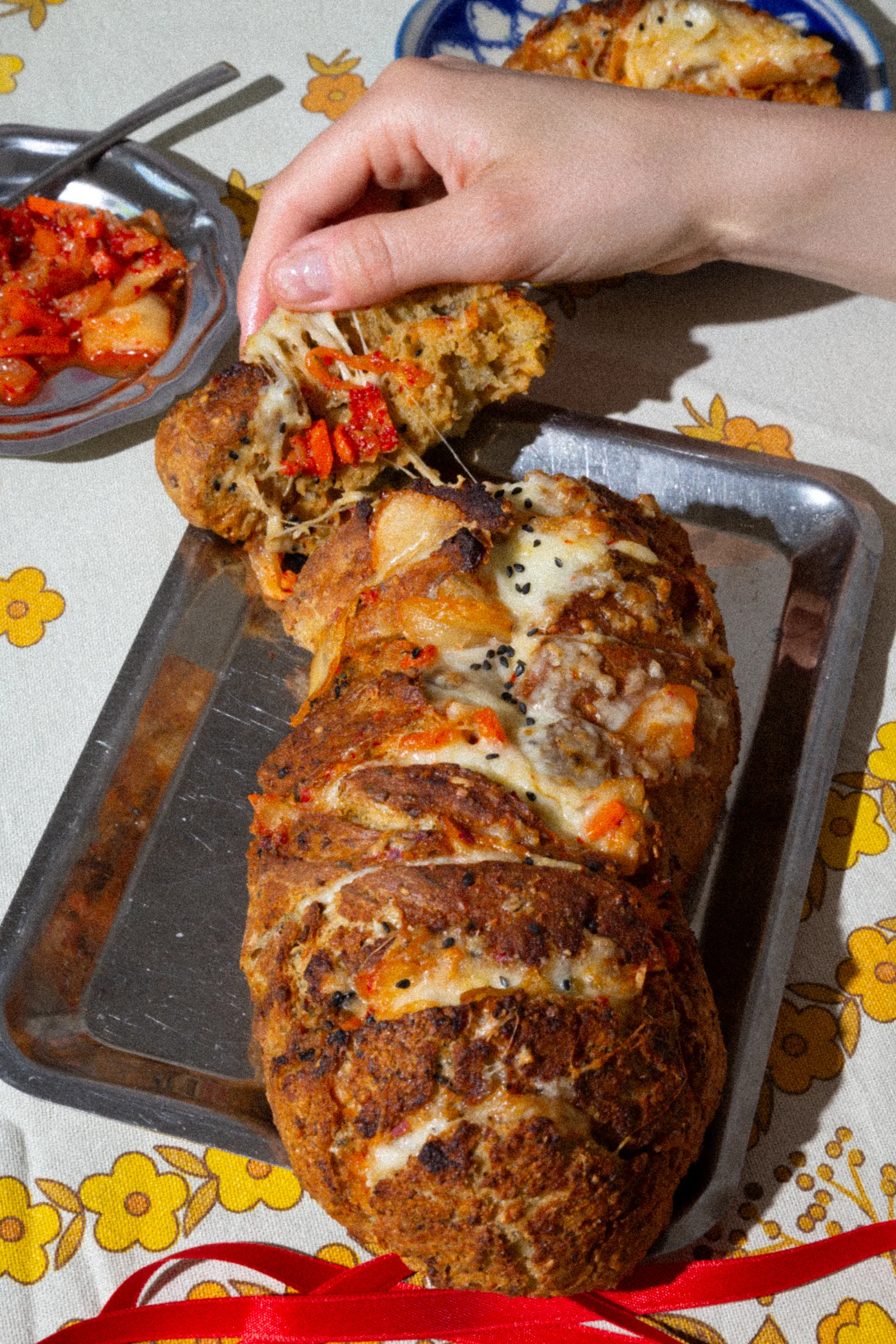 Kimcheese Zupfbrot mit Kimchi und Käse auf gelbem Blumendecke