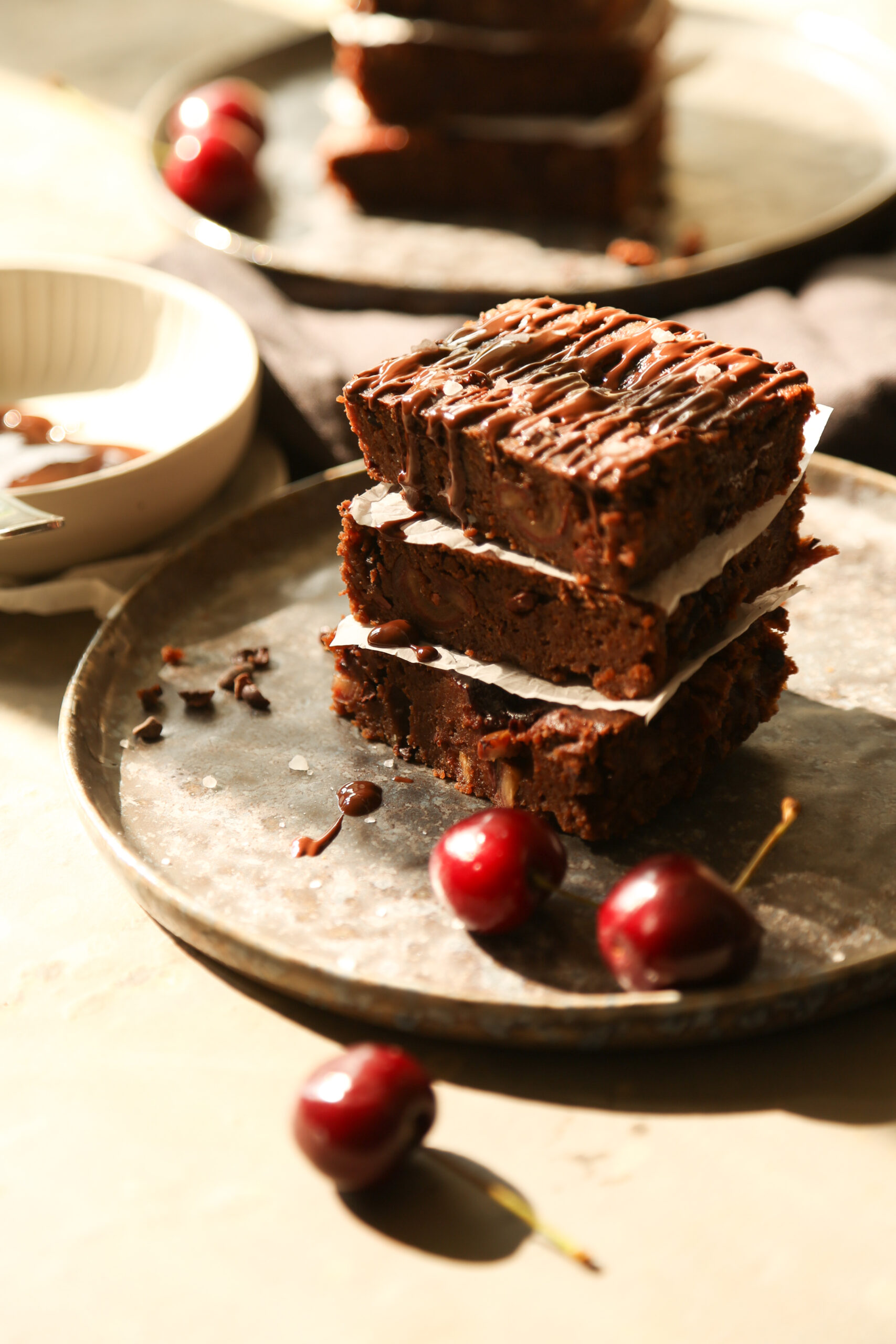 Gestapelte dunkelbraune Schokoladen-Kirsch Brownies, serviert mit frischen Kirschen.