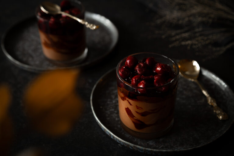 Moody fotografierte dunkle Mousse au Chocolat mit dunkelrotem Sauerkirschkompott.