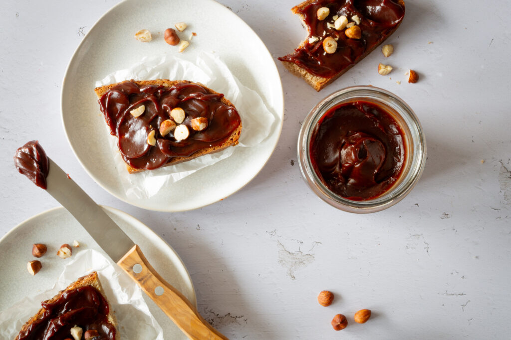 Brote mit dunkelbrauner Haselnuss-Schoko Creme, serviert mit gehakten Haselnüssen.