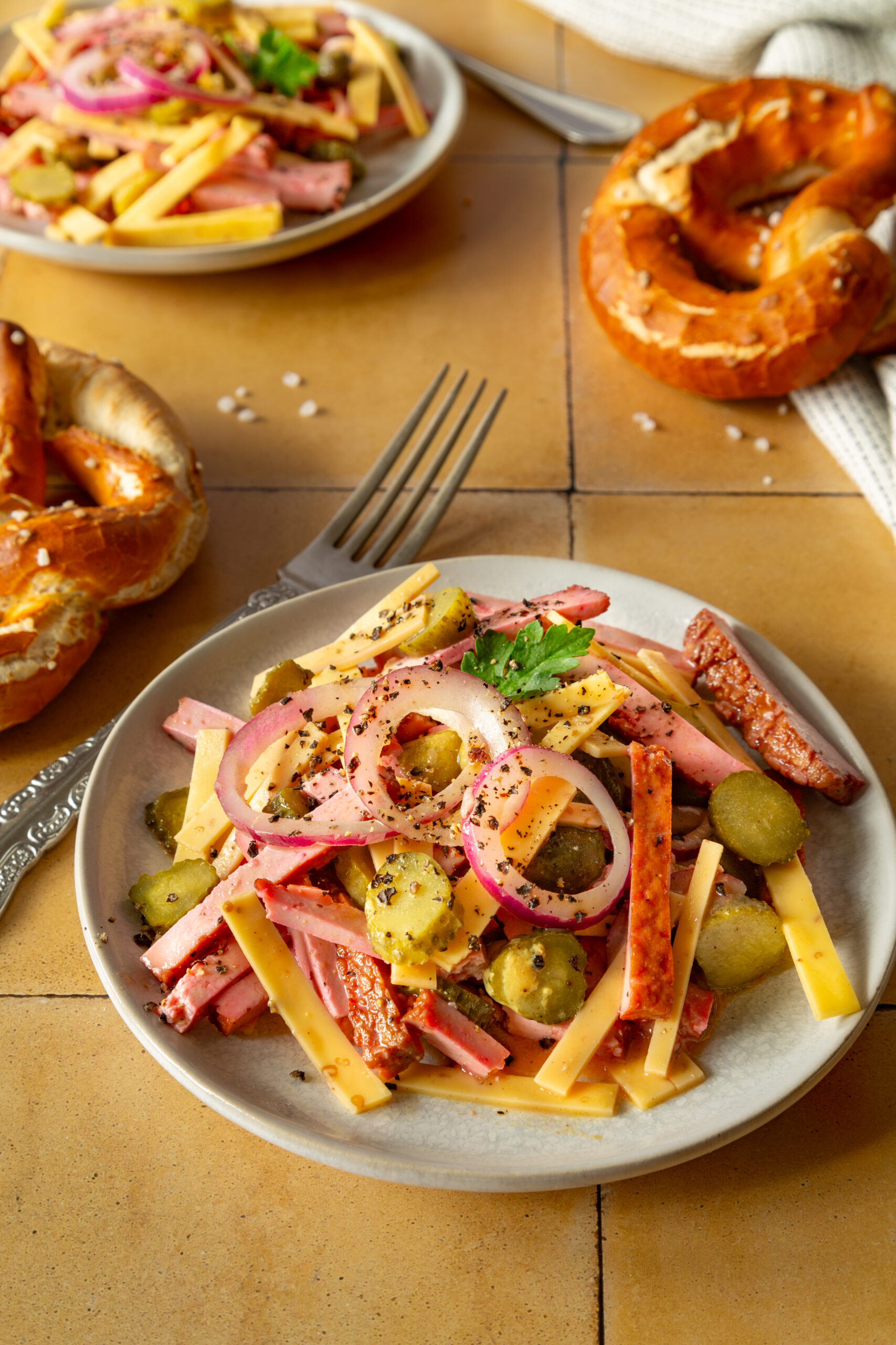 Salat mit Käse, Räuchertofu in Wurstsalatoptik, Gürkchen und Zwiebeln. Mit Brezen seviert