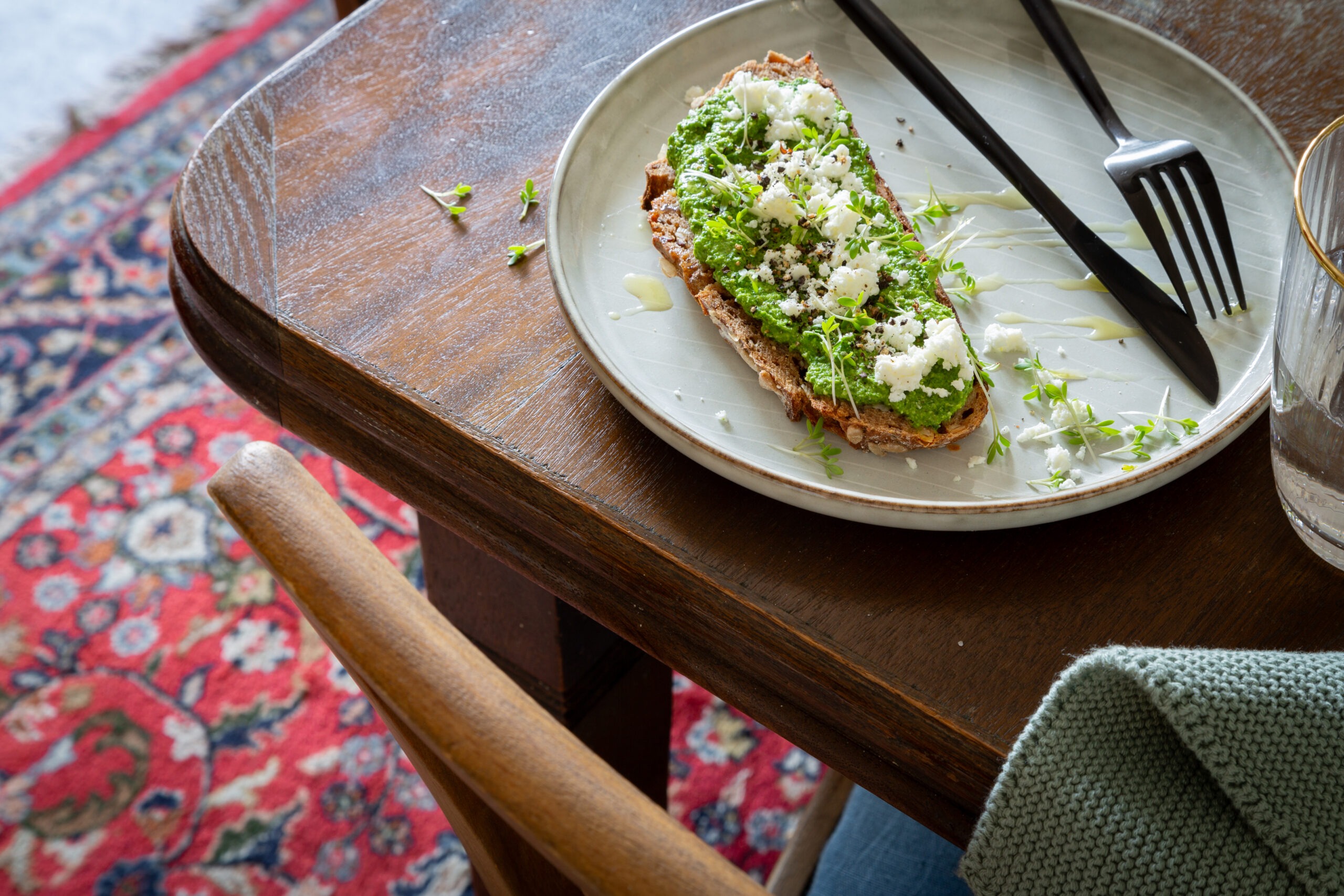 Tisch auf dem ein Teller steht mit Bärlauch-Pesto -Brot, getoppt mit Feta und Olivenöl.