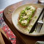 Tisch auf dem ein Teller steht mit Bärlauch-Pesto -Brot, getoppt mit Feta und Olivenöl.