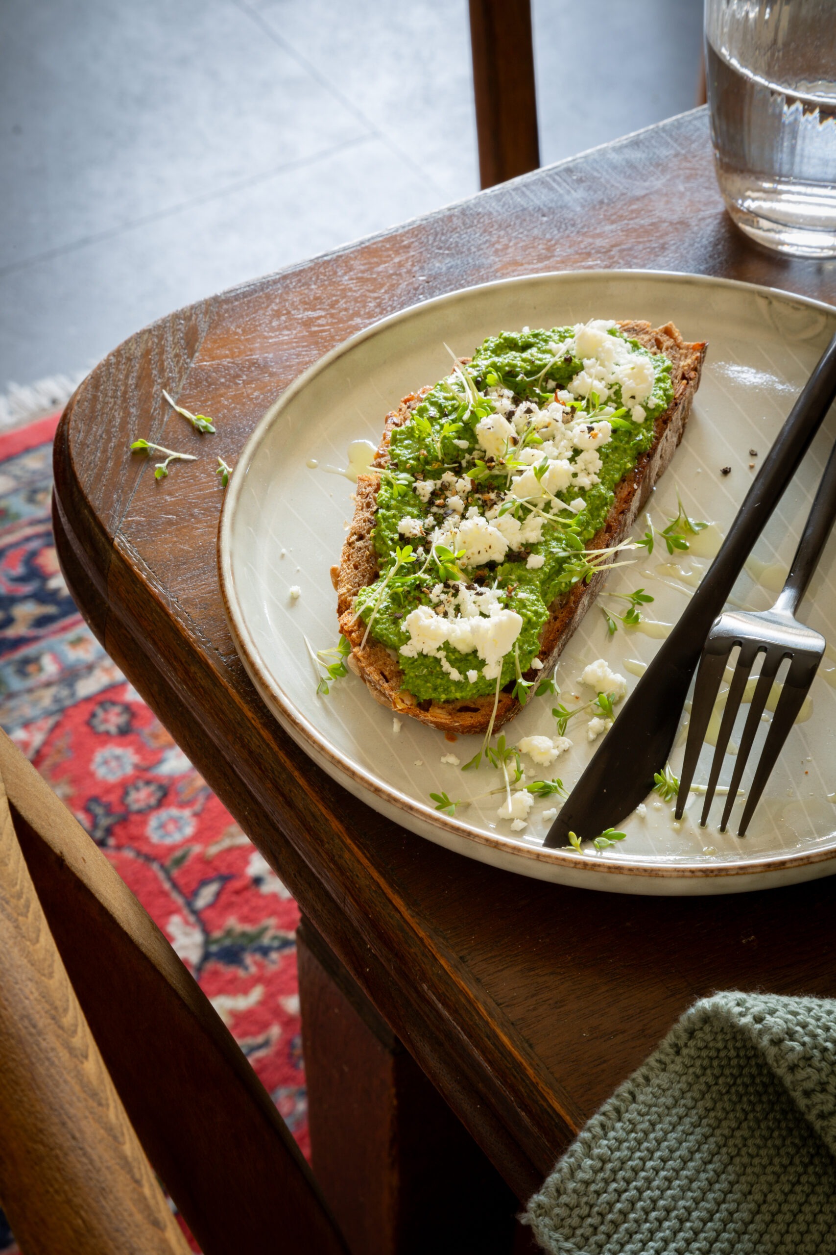 Tisch auf dem ein Teller steht mit Bärlauch-Pesto -Brot, getoppt mit Feta und Olivenöl.