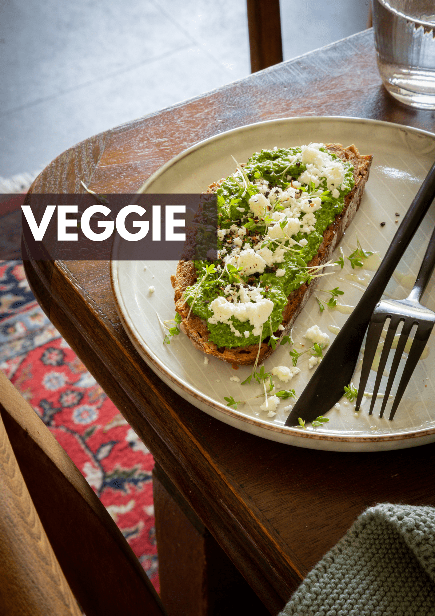 Tisch auf dem ein Teller steht mit Bärlauch-Pesto -Brot, getoppt mit Feta und Olivenöl.