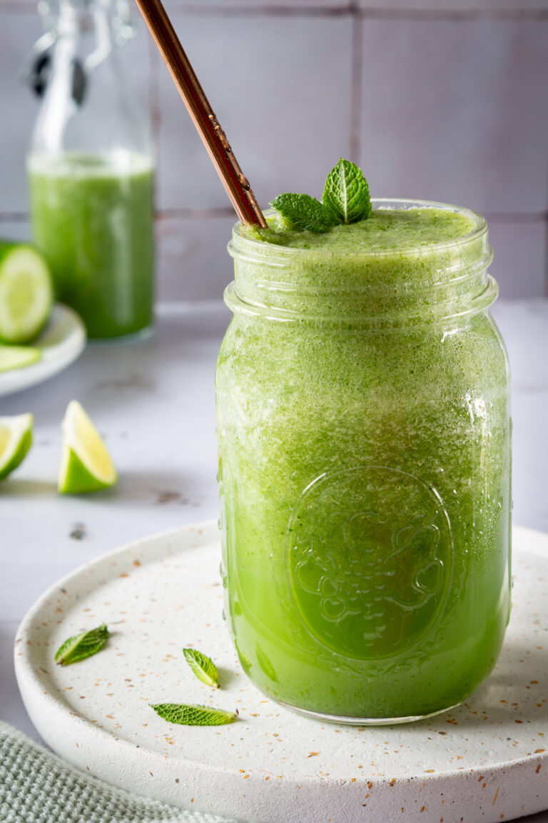 Grüner Smoothie aus Gurke und Minze in einem Schraubglas serviert und mit Minzblättchen dekoriert.