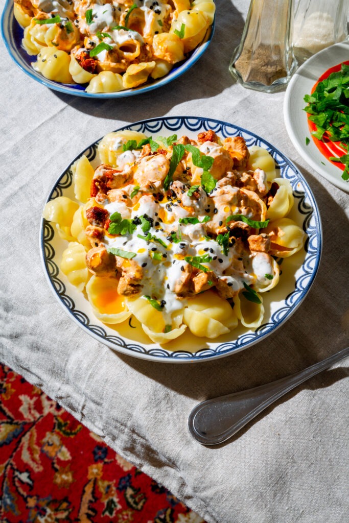 Pasta Manti Style serviert auf floralen Tellern auf einem Tisch mit Tischdecke.