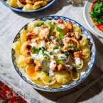 Pasta Manti Style serviert auf floralen Tellern auf einem Tisch mit Tischdecke.